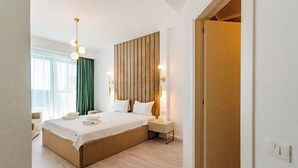 Una habitación de hotel moderna con una cama grande, lámparas de noche, cabecero de madera y vistas al exterior.