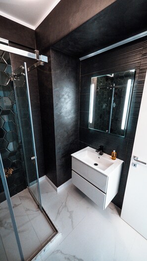 A modern bathroom with a glass shower enclosure, a white sink, and a large mirror. - Wave 4 Apartments (Navodari)