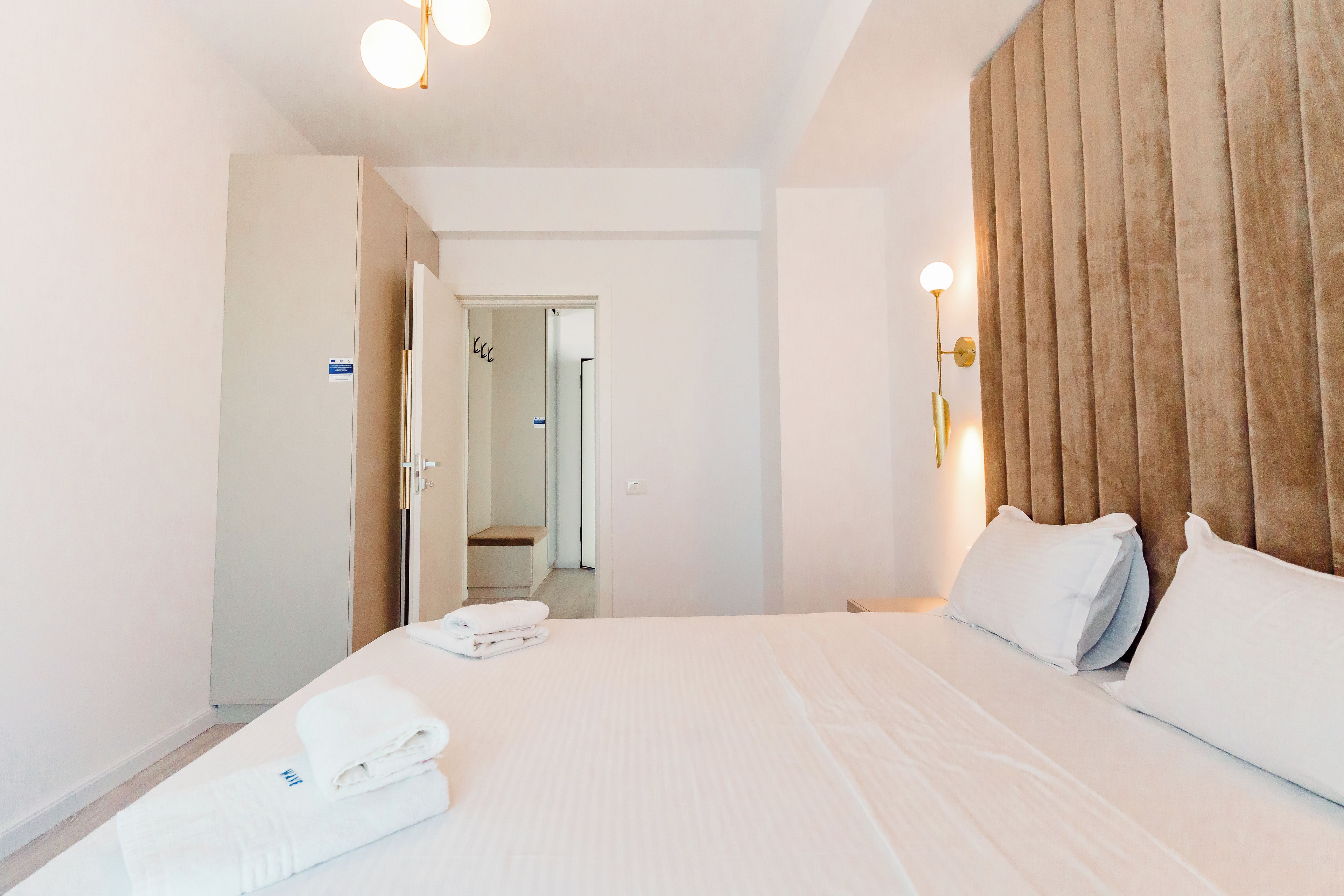 A hotel room with a large bed, a wooden headboard, and a bathroom visible through an open door.