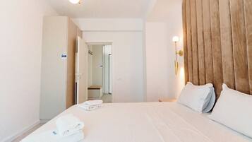 A hotel room with a large bed, a wooden headboard, and a bathroom visible through an open door.