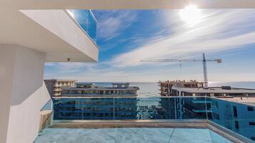 Una terraza en la azotea con vistas despejadas al mar y una grúa de construcción a lo lejos.