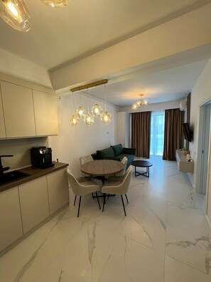 Cocina moderna con comedor, sofá y televisor.