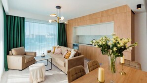 Una sala moderna con sofá, mesa de centro y mesa de comedor. Cuenta con una cocina con armarios de madera y vistas a la ciudad.
