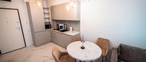 Una cocina compacta con una mesa redonda y sillas, un microondas y una cafetera.