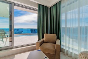 Une chambre moderne dotée d’une grande porte-fenêtre coulissante donnant sur un balcon avec vue sur la mer et un pont.