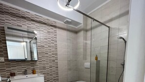 A modern bathroom with a glass shower enclosure, a vanity with a mirror, and a toilet.