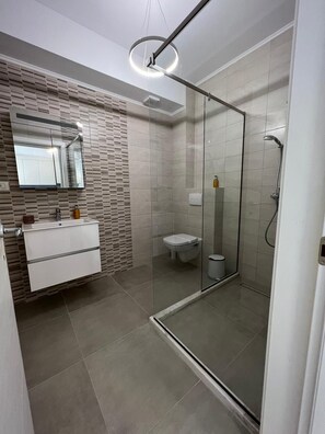 Une salle de bain moderne avec une douche à parois de verre, un meuble-lavabo avec un miroir et des toilettes.