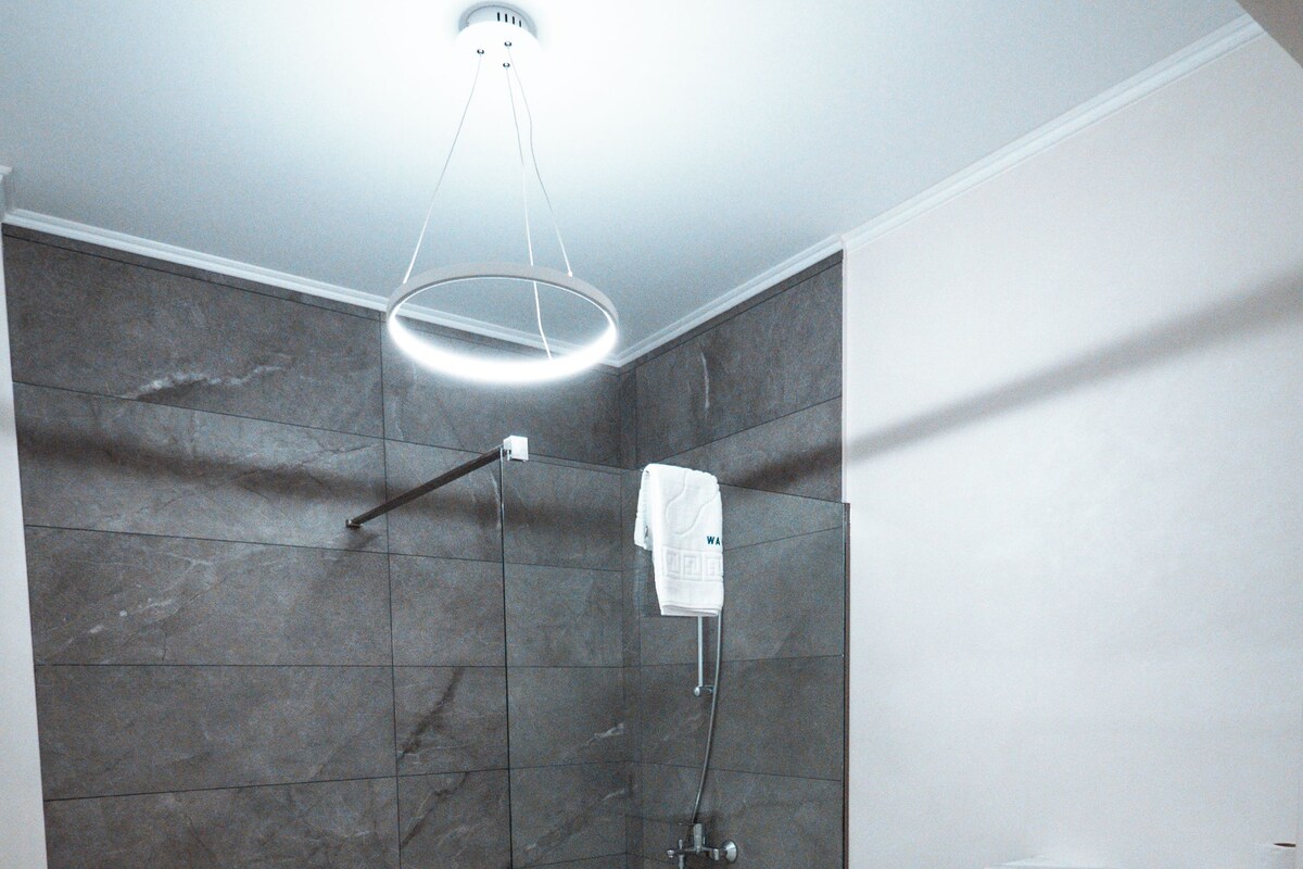 Une salle de bain moderne avec une douche en verre, un lavabo blanc et un sol carrelé en marbre.