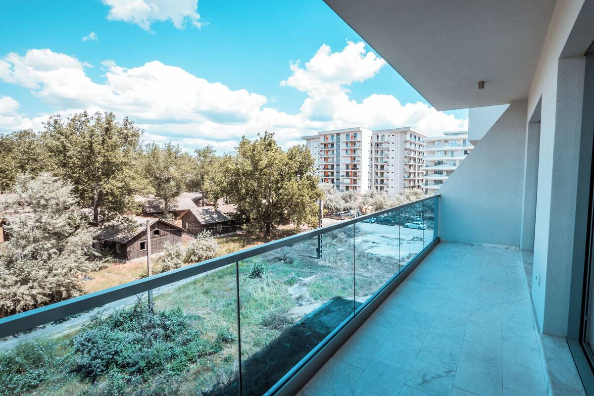 A balcony with a clear view of a residential area, including multi-story buildings and trees.