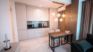 A compact kitchen with modern appliances, a dining area with a wooden table, and a cozy seating arrangement. - Wave 4 Apartments (Navodari)