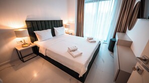 A hotel room with a large bed, two bedside tables with lamps, a dresser, and a window with curtains. - Wave 4 Apartments (Navodari)