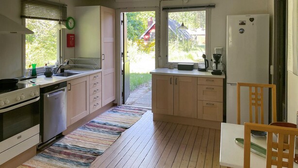 A kitchen with wooden cabinets, a stove, a sink, and a refrigerator. There is a window with a view of greenery outside. - 3 bedroom cozy home in Vig (Vig)