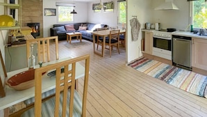 A cozy living area with a sofa, dining table, and chairs, a kitchen with a stove and sink, and a fireplace. - 3 bedroom cozy home in Vig (Vig)