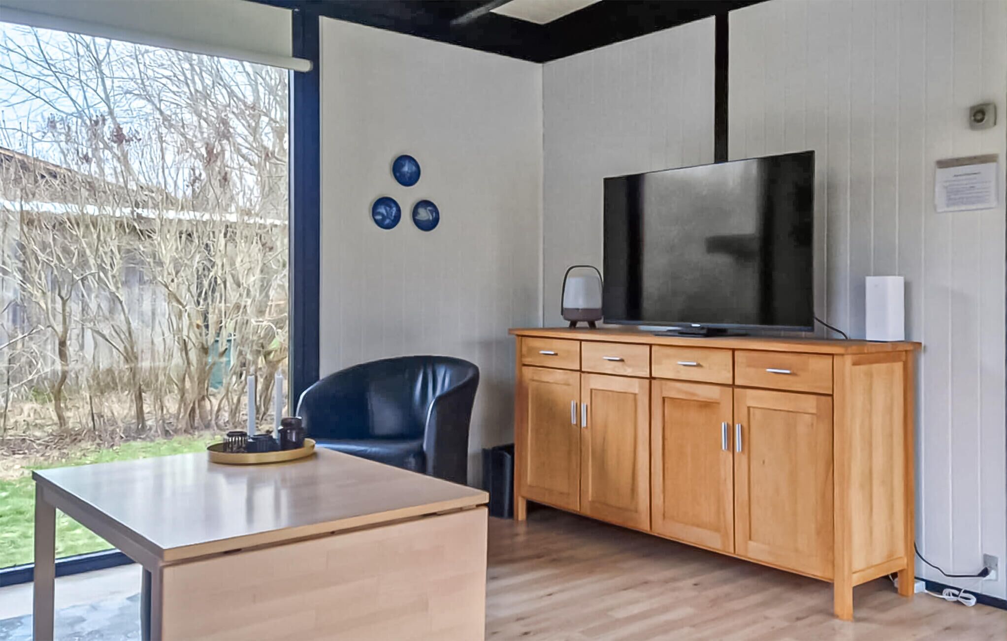 Une chambre moderne avec un meuble en bois, une télévision, une chaise et une table.