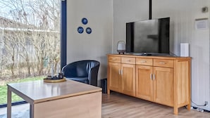 A modern room with a wooden cabinet, a television, a chair, and a table.