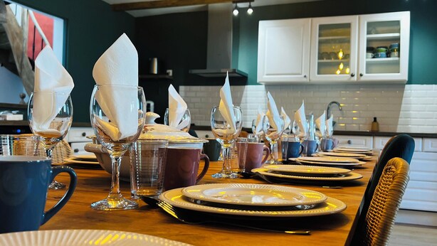 Comedor con mesa de madera dispuesta para una comida, con platos, vasos y servilletas.