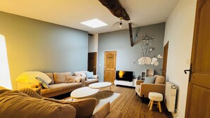 Una sala de estar acogedora con sofá, sillones, una mesa de centro y televisor.