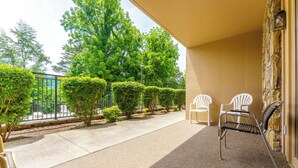 A balcony with a stone wall, two white chairs, and a wicker chair. - Holly Ridge 102 | Cozy, Near Gatlinburg + Privacy (Gatlinburg)