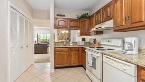 A kitchen with wooden cabinets, a stove, a dishwasher, and a countertop with appliances. - Holly Ridge 102 | Cozy, Near Gatlinburg + Privacy (Gatlinburg)