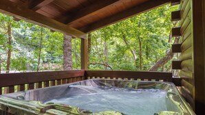 A hot tub in a wooden cabin with a view of a forest. - Mountain Falls 14 | Family Friendly + Hot Tub (Sevierville)