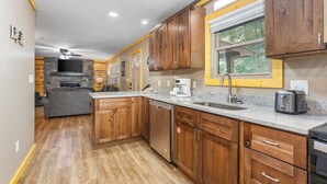 A modern kitchen with wooden cabinets, granite countertops, a dishwasher, and a built-in oven.