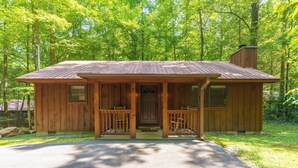 A wooden cabin with a porch, a chimney, and a front door.
