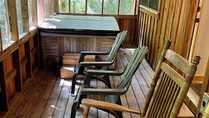 Una terraza de madera con mesa y sillas, ventanas amplias y vistas al exterior.