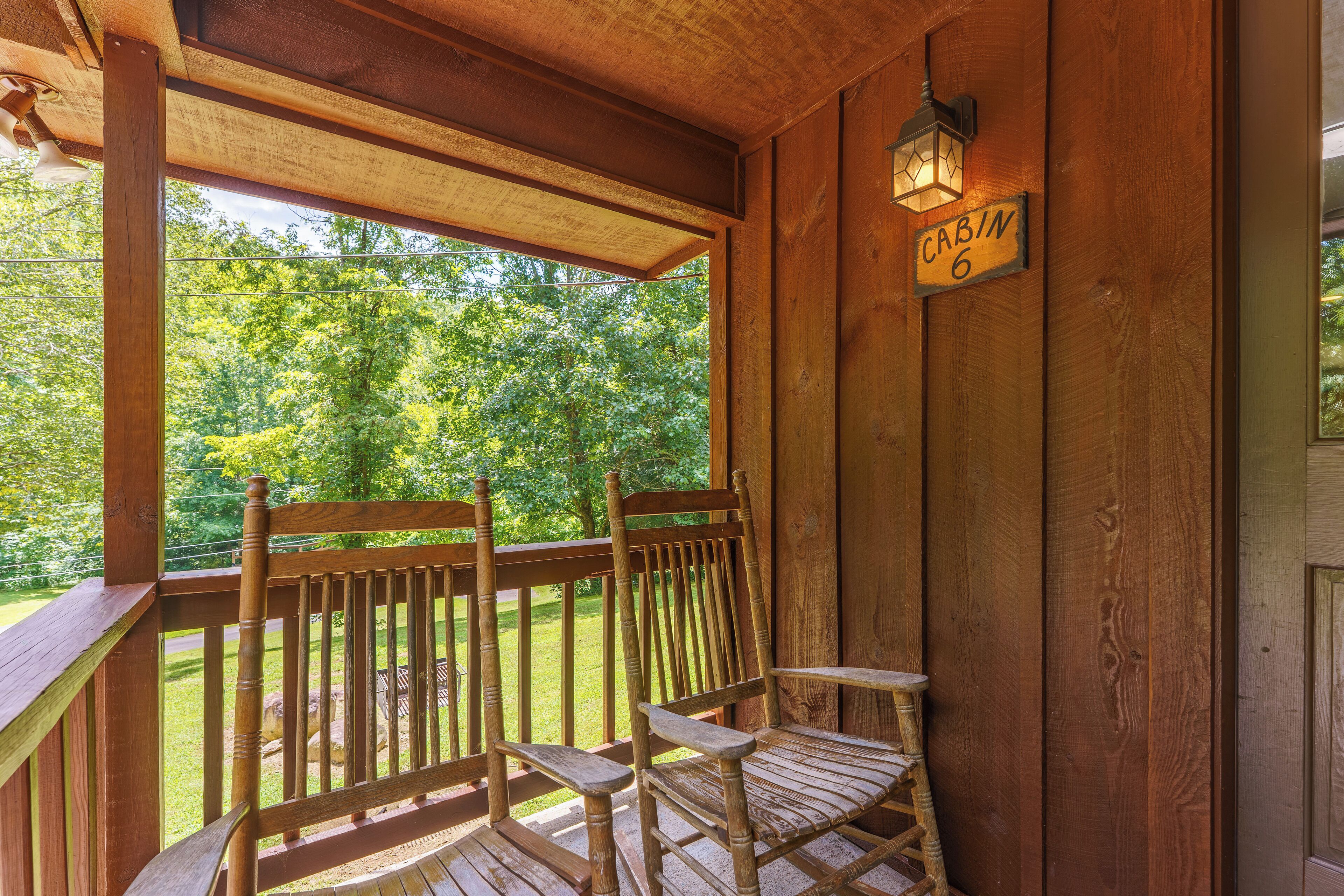 A wooden porch with a bench and a sign reading "CABIN 6".