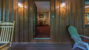 Une façade en bois avec une porte donnant sur un espace de restauration intérieur, comprenant une table et des chaises.
