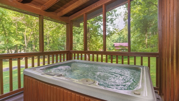 Un bain à remous sur une terrasse en bois, avec vue sur une forêt.