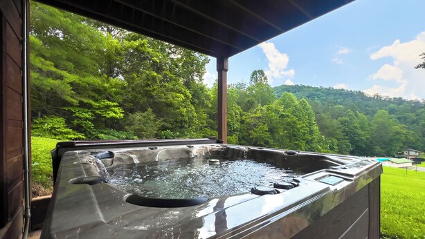 Un jacuzzi con vistas a un bosque verde exuberante y un cielo azul despejado.