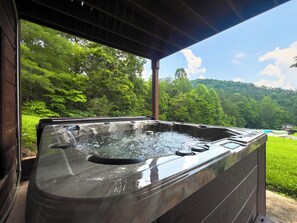 Un bain à remous avec vue sur une forêt verdoyante et un ciel bleu azur.