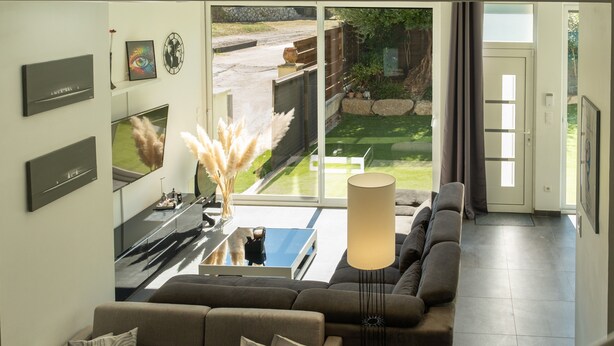Un salon moderne avec une grande fenêtre, un canapé, une table basse et une lampe.