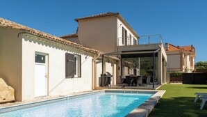 Une piscine avec un espace patio, un coin salon extérieur couvert et une vue sur une colline.