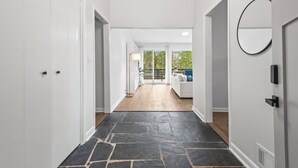 A hallway with a stone floor, white walls, and a view of a balcony with a white sofa.