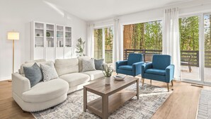 A modern living room with a sofa, two armchairs, a coffee table, and a bookshelf.