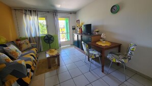 Un salon avec un canapé, une table à manger et des chaises, un téléviseur et un ventilateur.