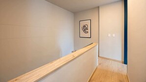 A hallway with a wooden bench, a framed picture on the wall, and a light switch.