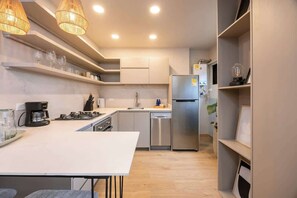 A modern kitchen with white cabinetry, a stainless steel refrigerator, a coffee maker, and a sink. - Digital Nomad Paradise 2BR unit with A/C in Manila (Medellín)