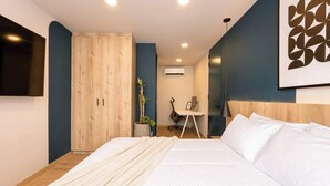 A bedroom with a bed, a desk, and a wardrobe.