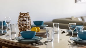 Een eettafel gedekt met blauwe kommen, borden en glazen, met een geweven mand en citroenen op de achtergrond.