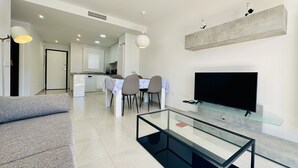 Un salon moderne avec une table basse en verre, un téléviseur à écran plat et un canapé.