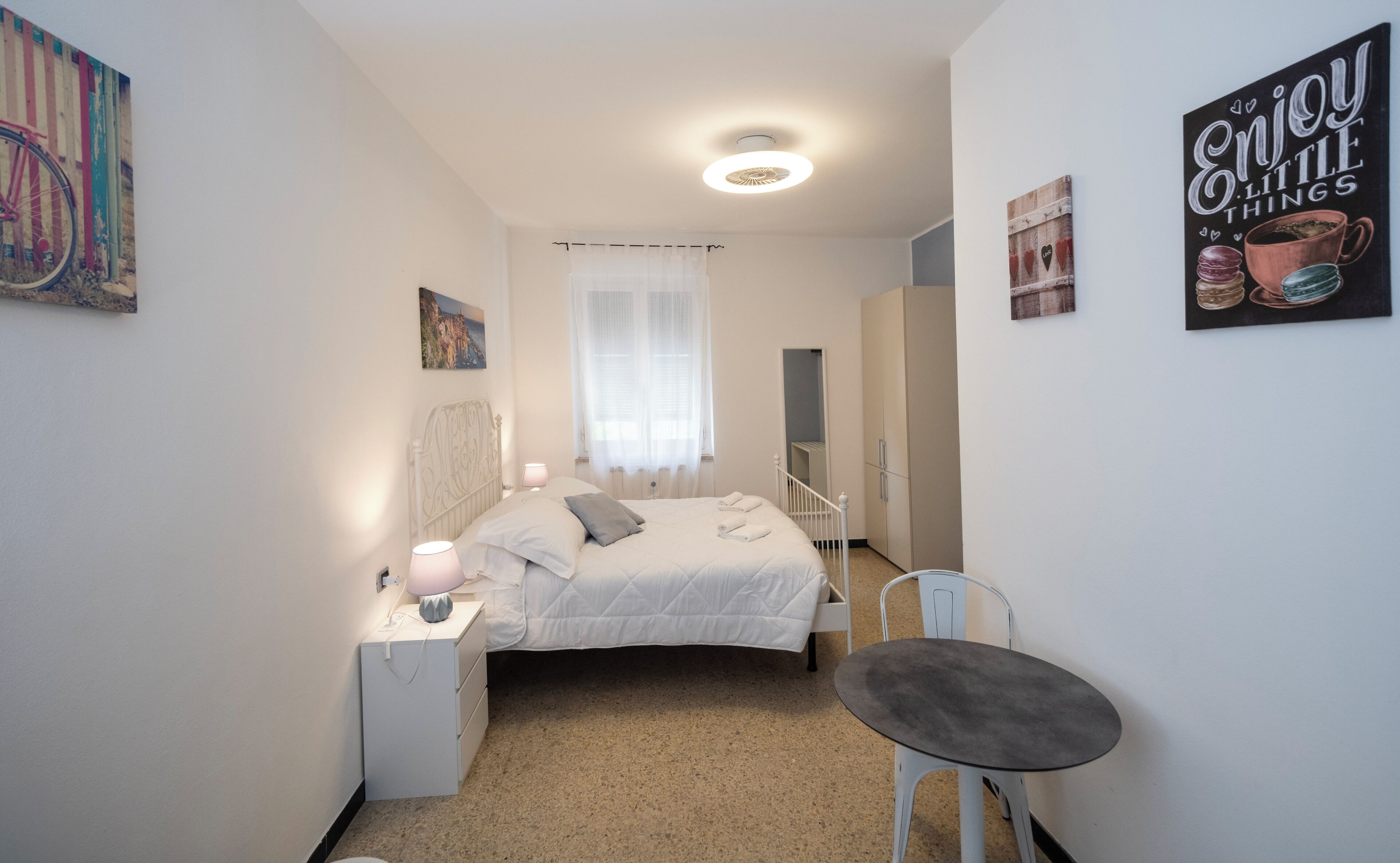 Un dormitorio con cama, mesita de noche, silla y un cuadro en la pared.