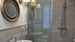 A modern bathroom with a glass-enclosed shower, a white sink with a towel, and a round mirror. - Pippo a vernazza rooms (Vernazza)