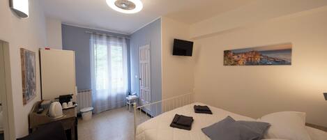 Une chambre d’hôtel avec un lit, un bureau, une chaise, une télévision et un tableau au mur.