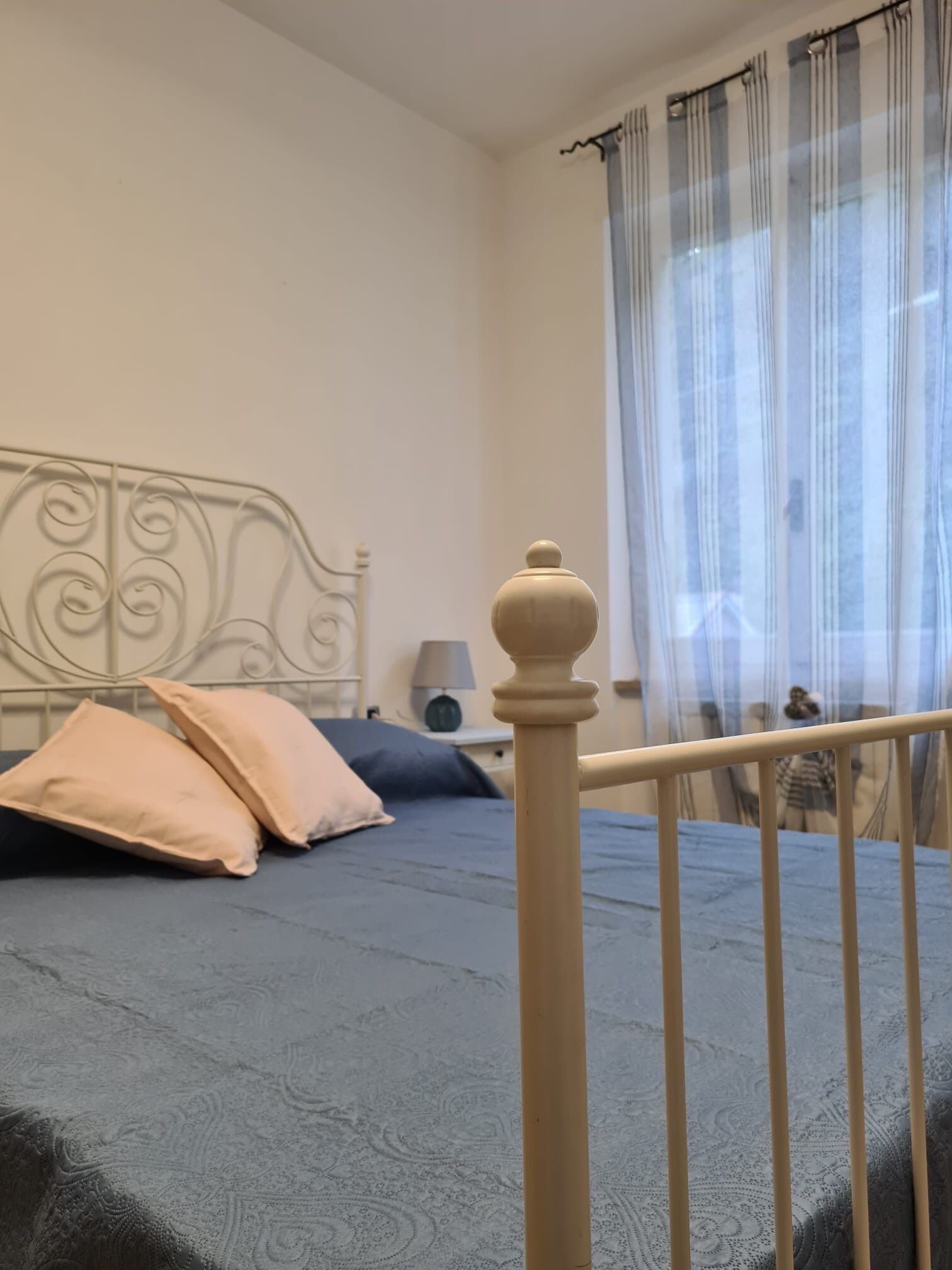 A bedroom with a bed, a bedside table, a lamp, and a window with curtains.