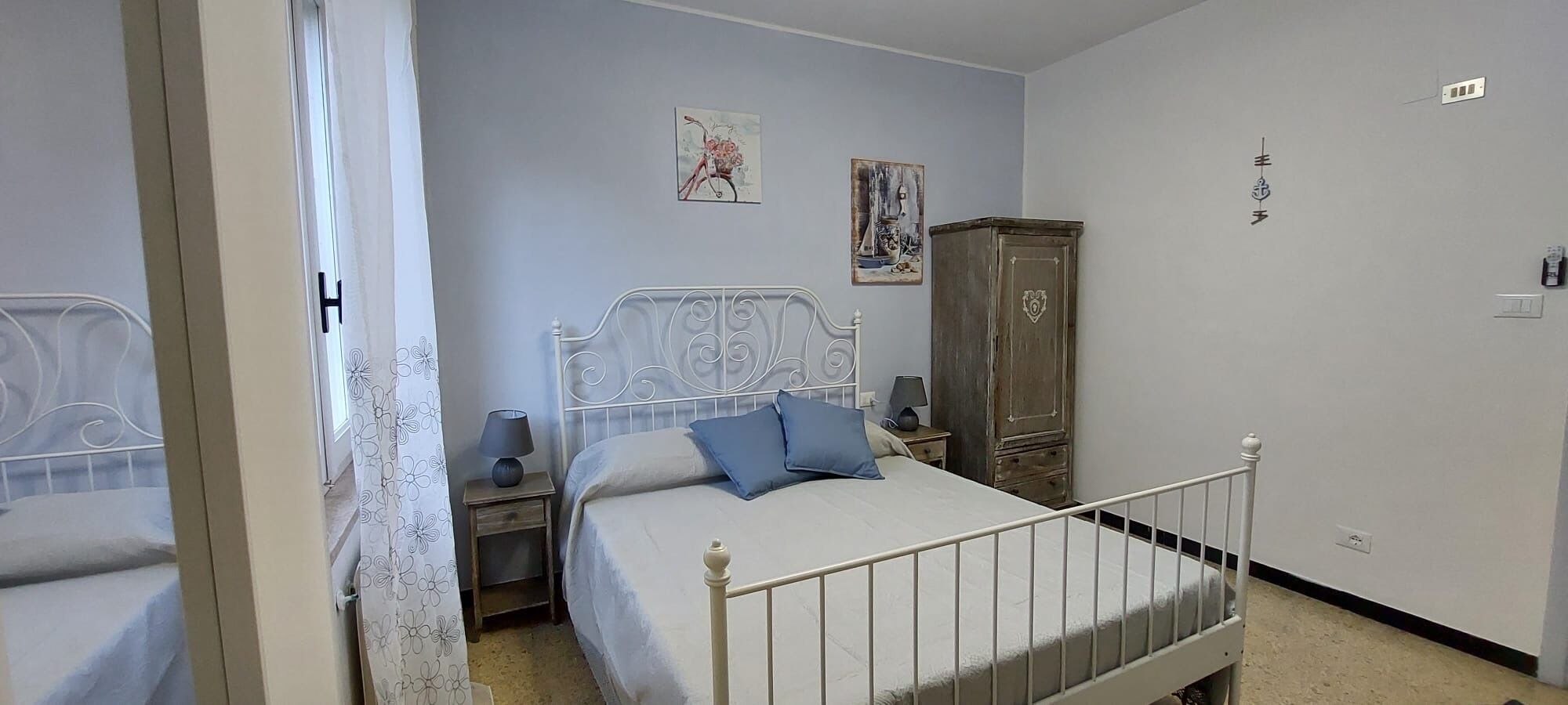 A bedroom with a bed, a nightstand, a wardrobe, and a mirror.