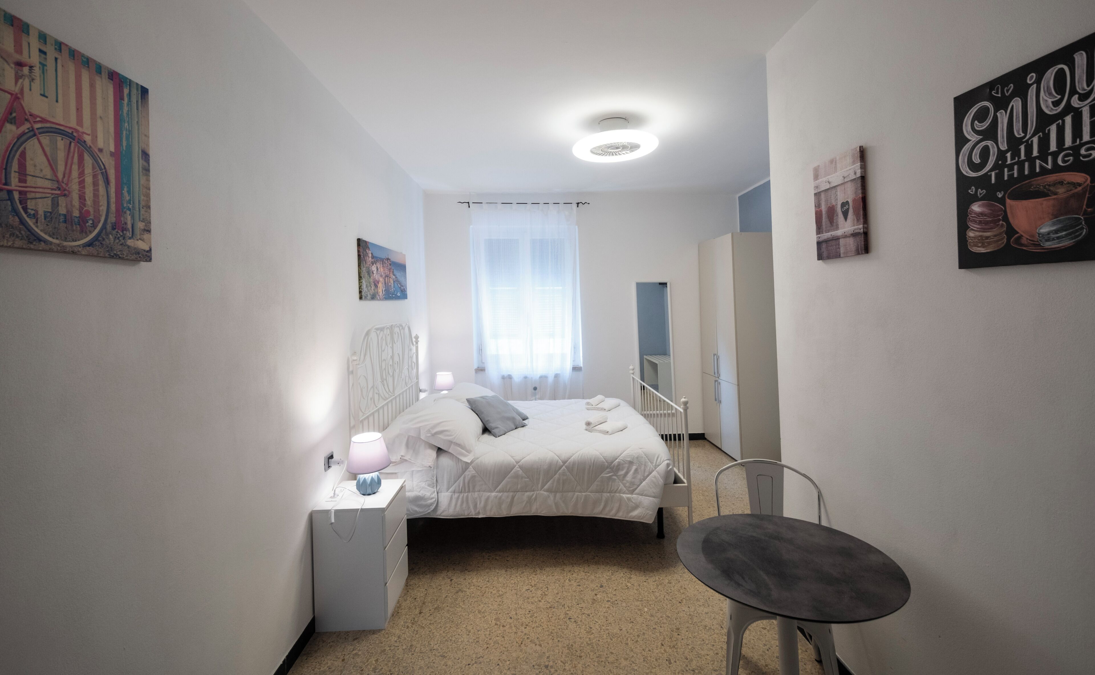 Une chambre à coucher avec un lit, une table de chevet, une chaise et des œuvres d’art accrochées aux murs.