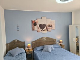 Un dormitorio con dos camas, una obra de arte en la pared y un armario.