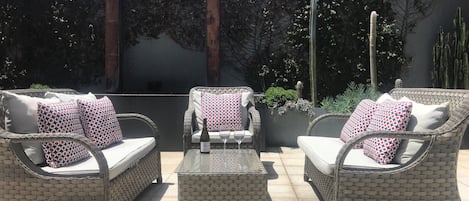 An outdoor patio area with wicker furniture, including two sofas and a chair, each with patterned cushions.
